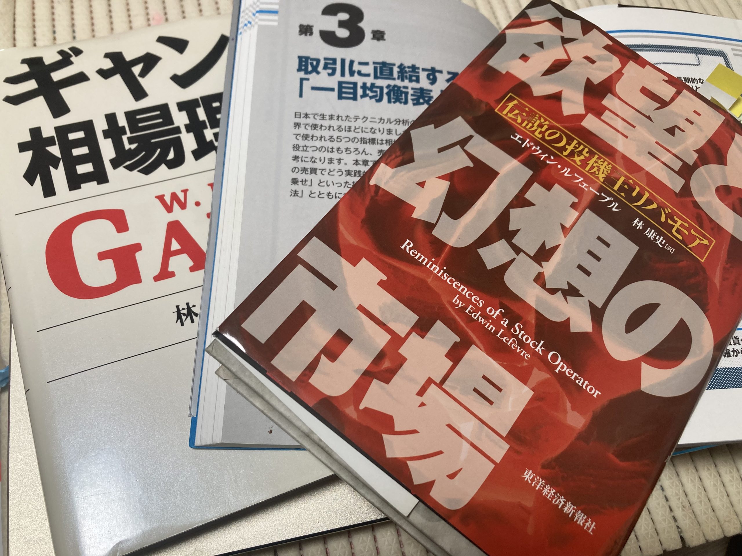 ジェシー・リバモア『欲望と幻想の市場』、W.D.ギャン『ギャン相場理論』、一目均衡表の解説書が重なっている写真。投資哲学の融合を象徴。